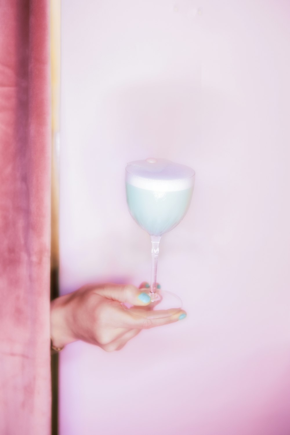 a hand holding a glass of blue liquid