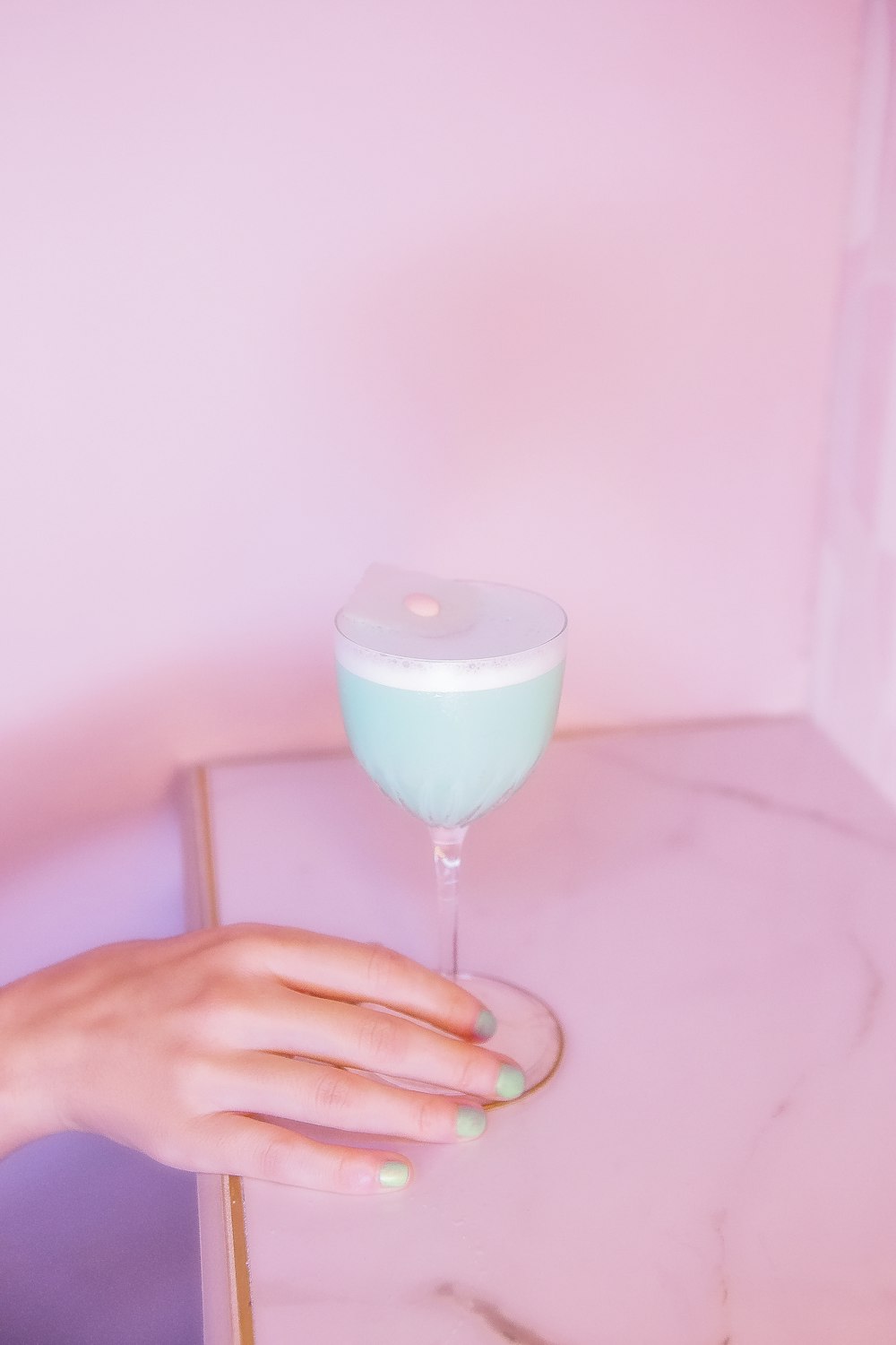 a hand holding a glass of blue liquid