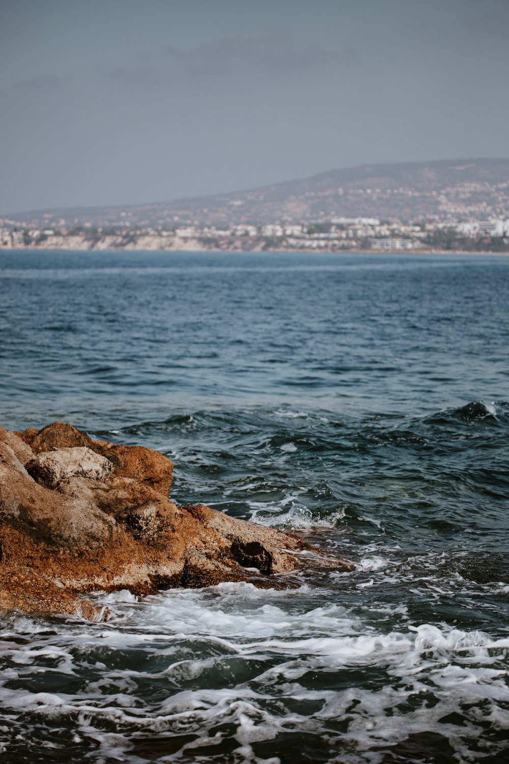 a rocky beach with a city in the background