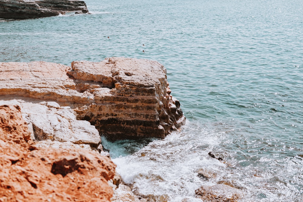 a rocky cliff next to a body of water