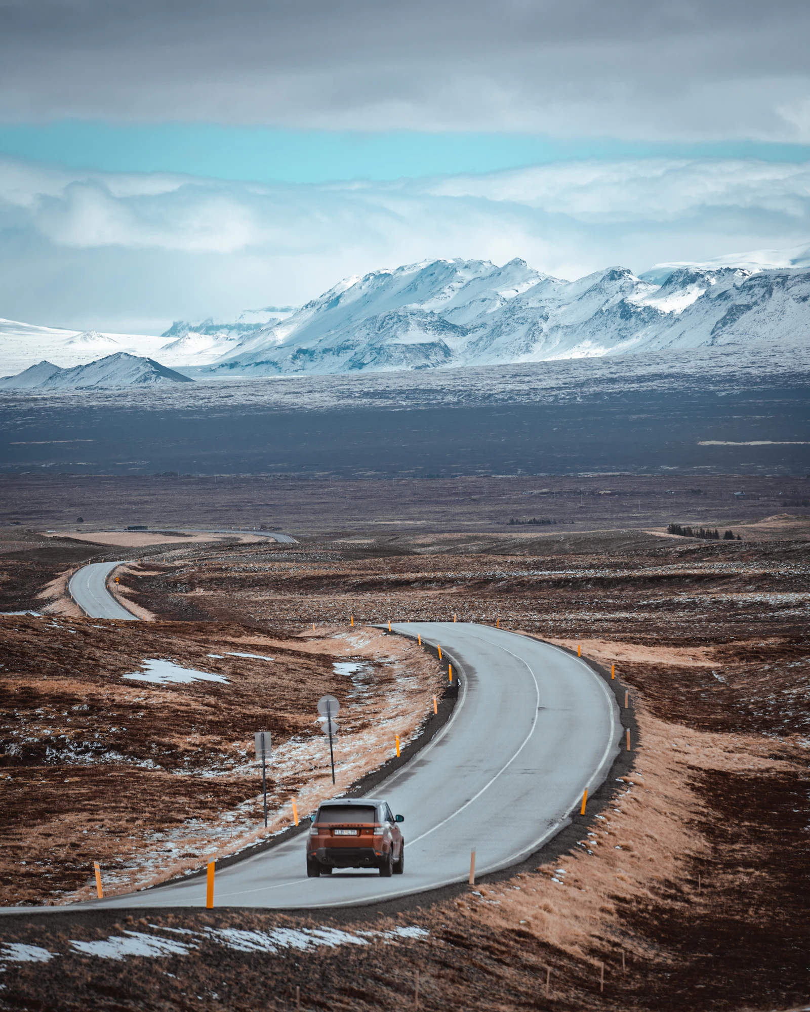 A car stopped safely on an Icelandic road beneath a mountain