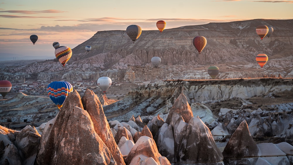 a group of hot air balloons flying over a rocky landscape