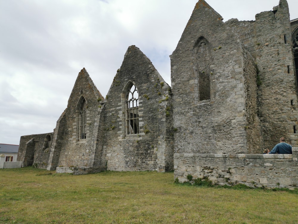 a person sitting on a bench in front of a stone building