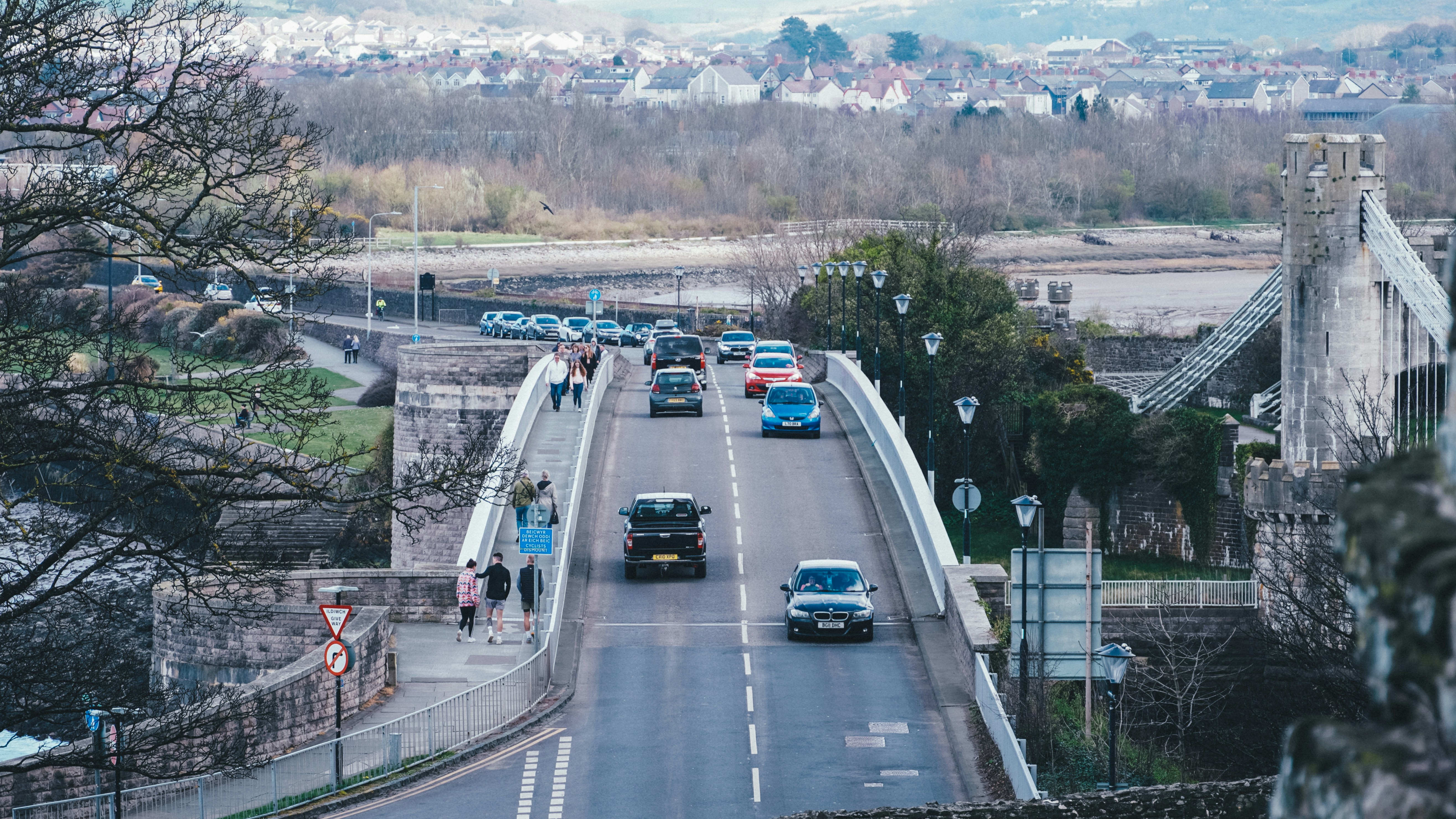 a road with cars on it and people walking on the side