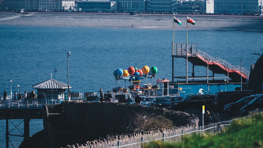 a body of water with balloons and cars by it