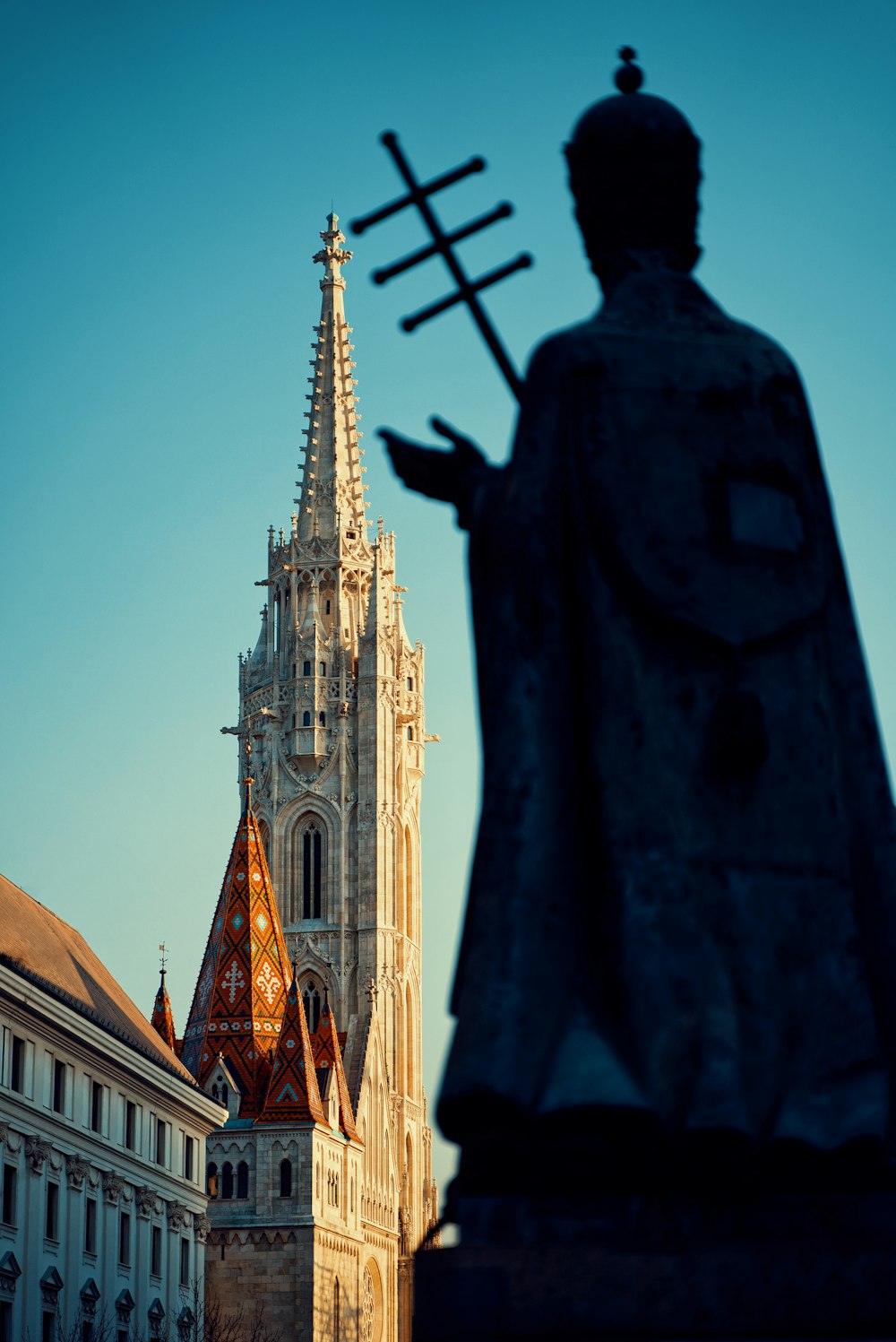 a statue of a person holding a cross in front of a tall building