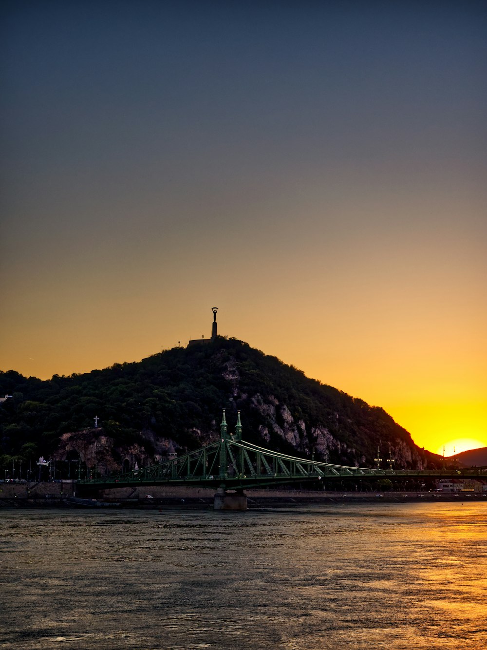 a bridge over water with a hill in the background