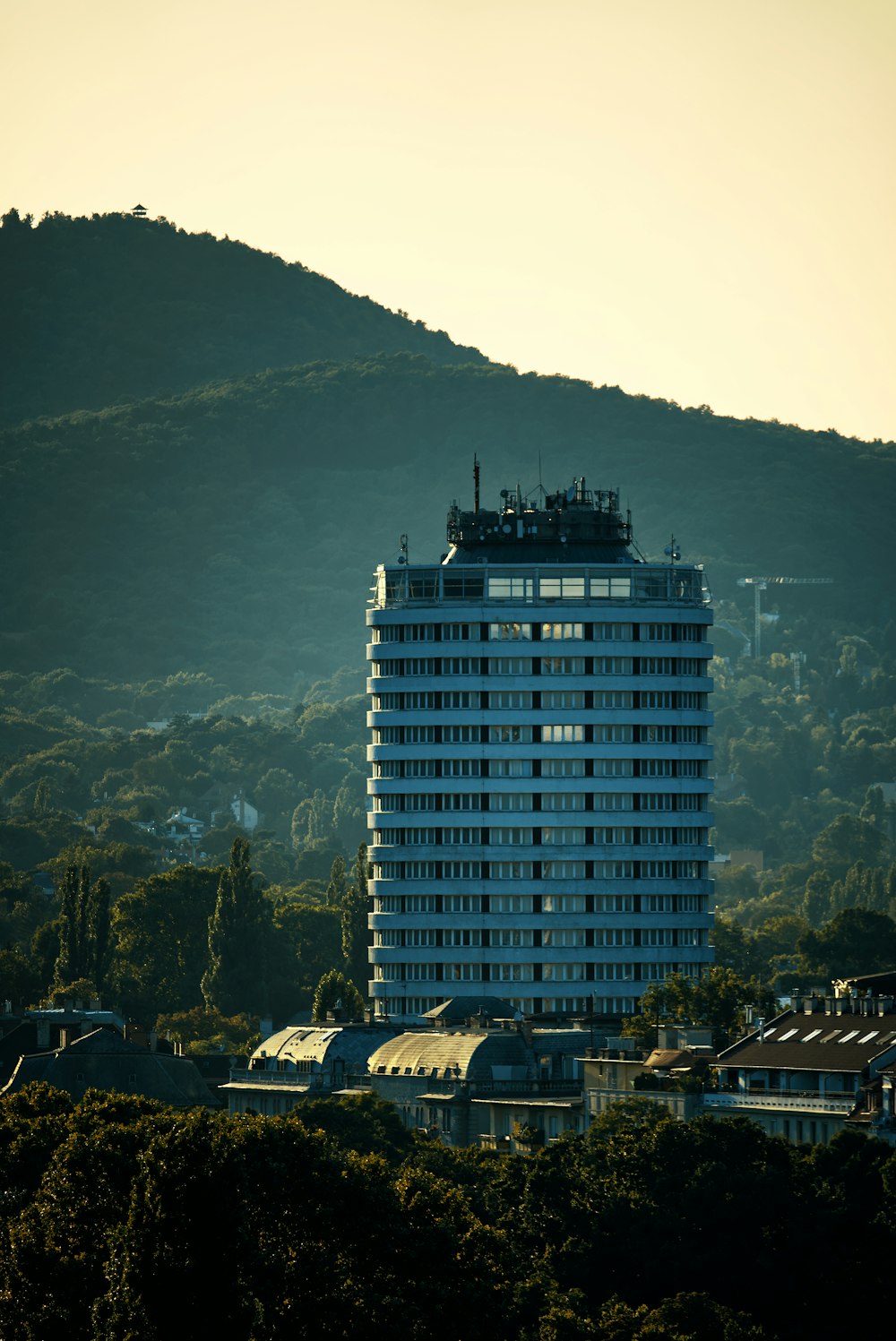 a tall building with a hill in the background