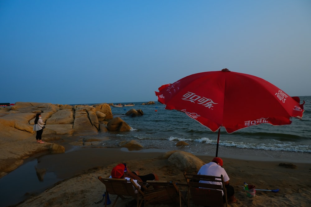 people sitting under an umbrella on a beach