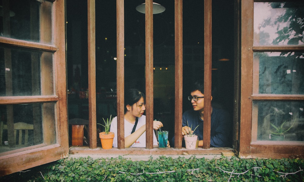 a man and woman sitting in a window