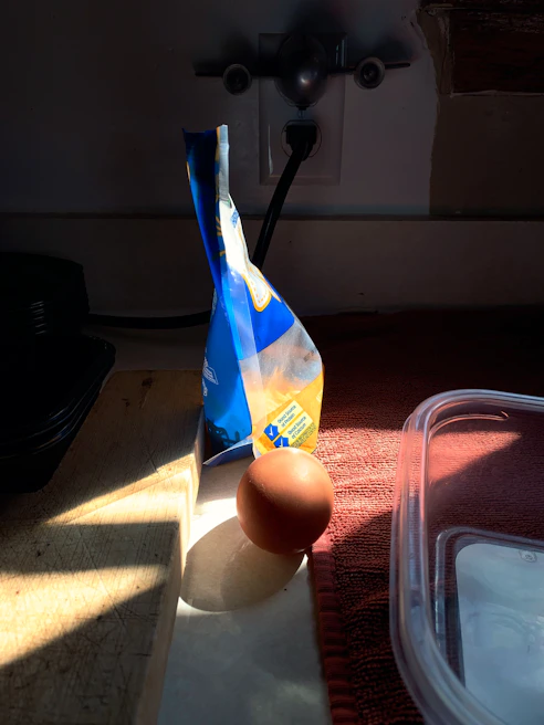 Freshly cracked eggs next to a bowl of fine, pale egg powder on a kitchen counter