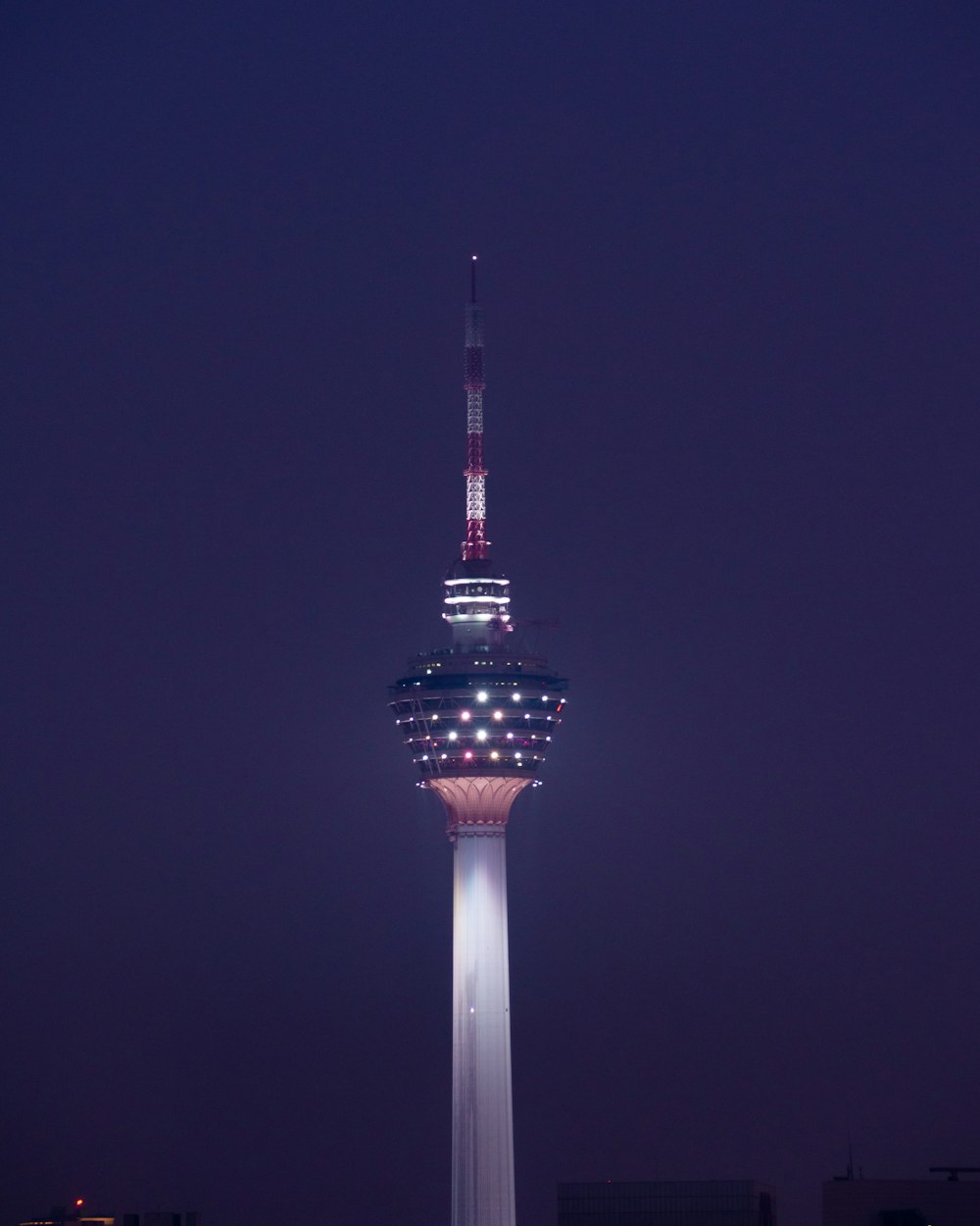 a tall pointy tower with lights at night