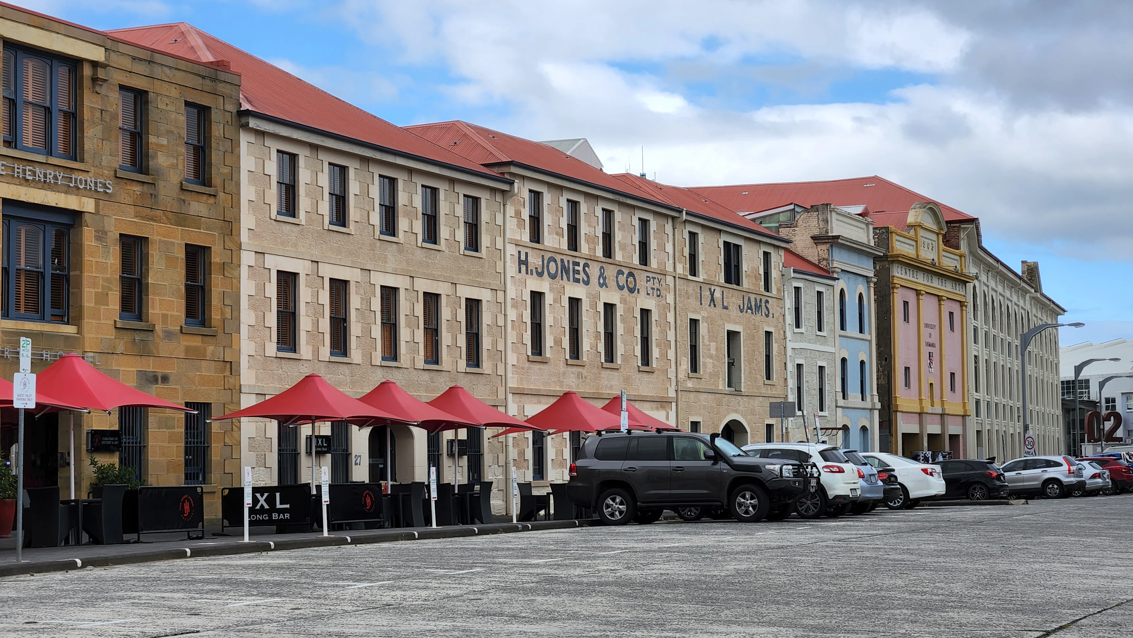 Sandstone warehouses with red café umbrellas along Salamanca Place, Hobart