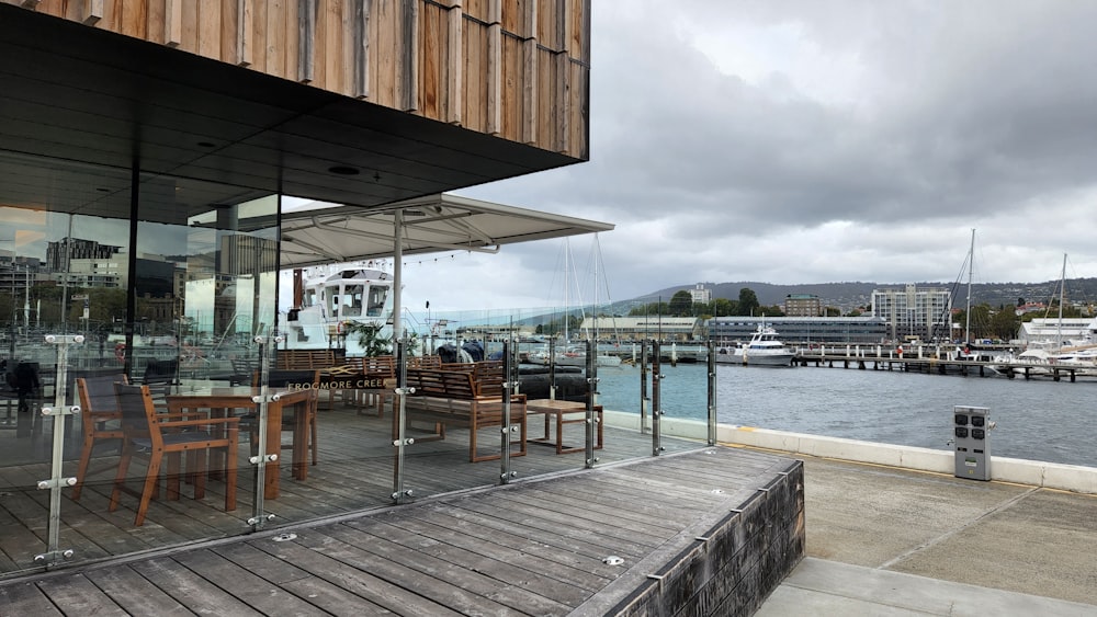 a wood deck with tables and chairs by a body of water