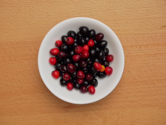 Close-up of vibrant freeze-dried edible cornelian cherry berries in a rustic wooden bowl