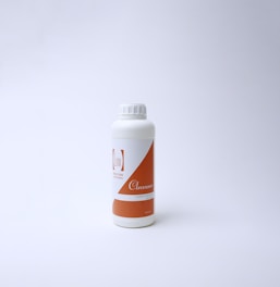 A white plastic bottle with an orange label on a plain white background. The label features text including the word 'Cleanser' and a logo with minimalistic design. The bottle has a screw cap and is positioned slightly to the left of the center.