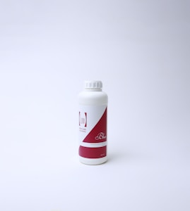 A white plastic bottle with a red and white label featuring text. The bottle has a screw cap and is standing on a white surface with a light background, suggesting a clean and minimal presentation.