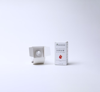 A skincare product displayed against a plain white background. On the right, a box labeled 'Anti-Dark Spot Serum' with a droplet graphic is standing upright. To the left of the box, the box is open and reveals a white bottle nestled inside.