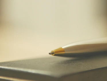 Close-up of a metallic pen with tactile embossing resting on a minimalist white background.