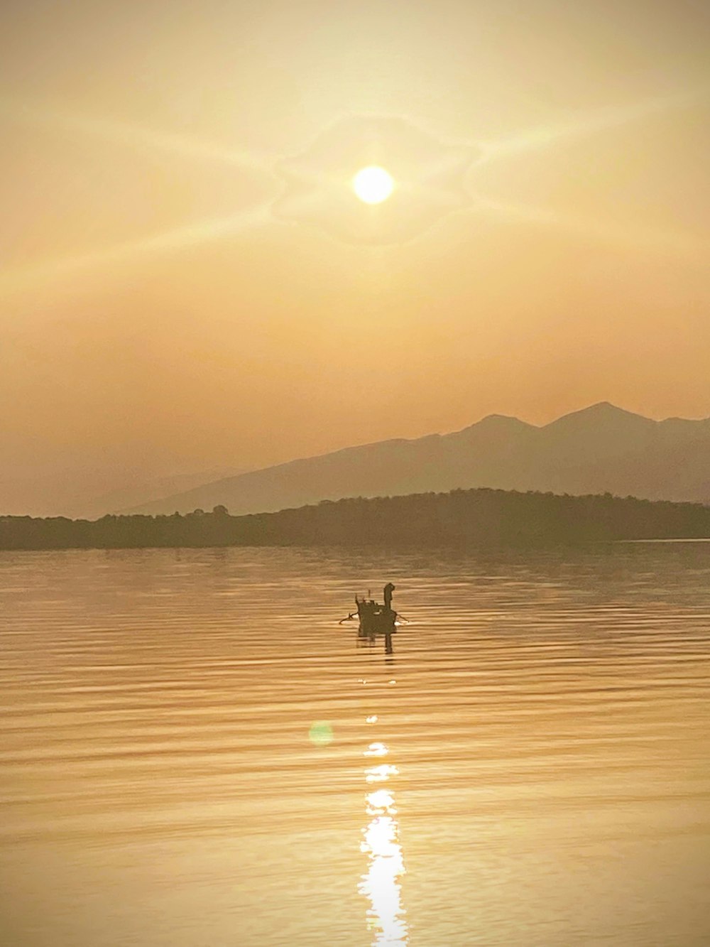 a couple people in a boat on a lake with the sun setting