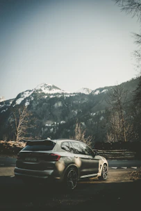 Silver SUV parked on a mountain road with scenic forest background