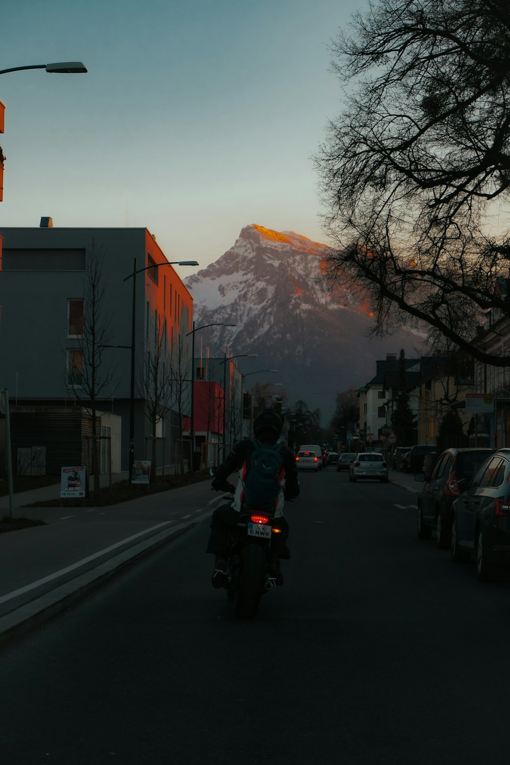 une personne conduisant une moto dans une rue avec une montagne en arrière-plan
