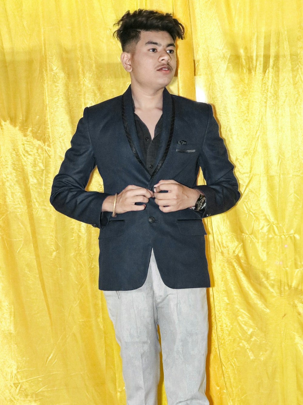 a person standing in front of a yellow curtain