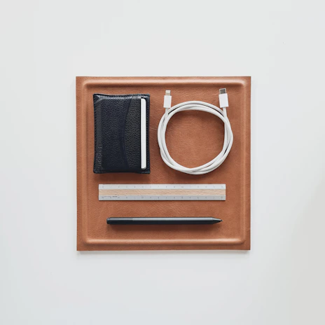 Overhead shot of a minimalist travel setup featuring a Glaxmix wallet, keys, phone, and sunglasses arranged neatly on a charcoal surface.
