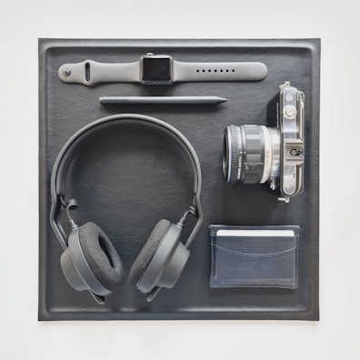 Flat lay of sports accessories including branded wristbands, water bottles, and headphones on a black background.