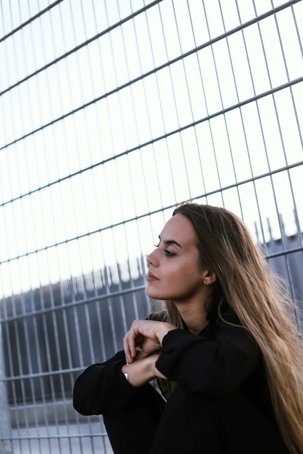 a woman leaning against a metal fence