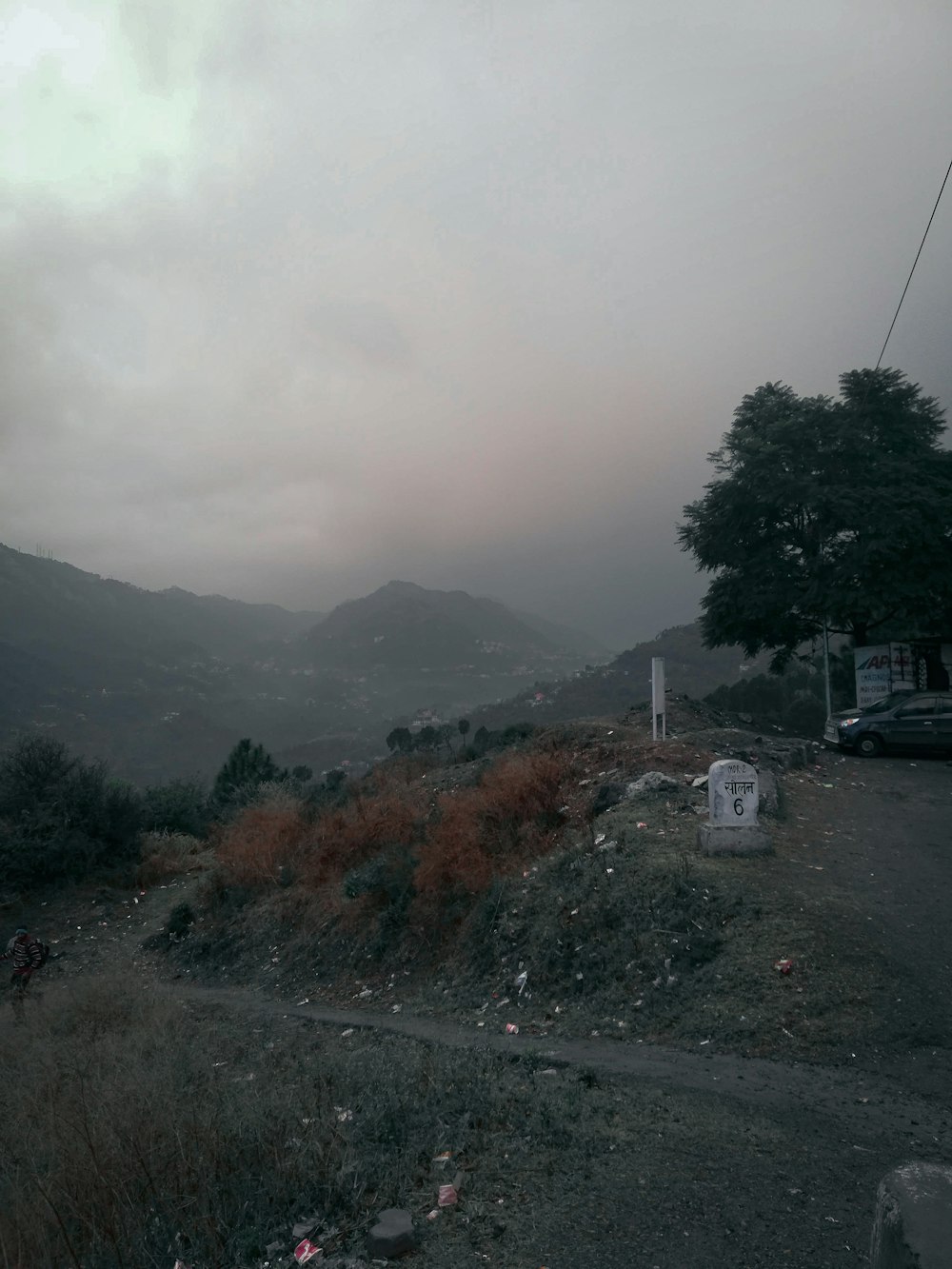 une route avec une voiture dessus et une colline avec des arbres et un bâtiment dessus