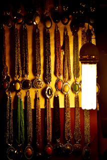 Display of various crystal necklaces hanging gracefully on a pastel blue wall with subtle shadows