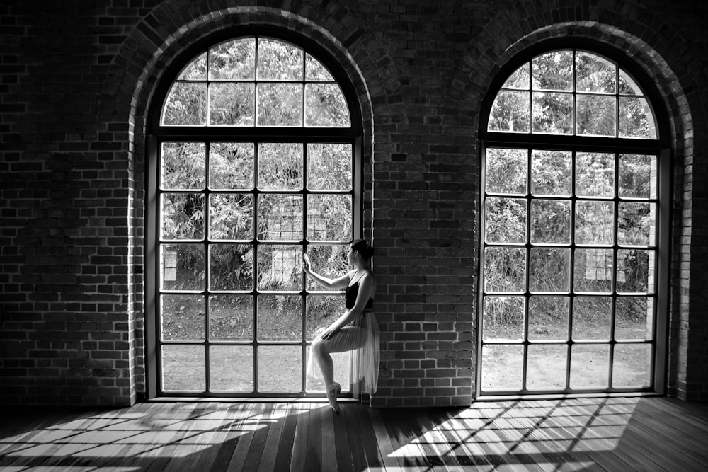 a person in a dress dancing in a room with large windows