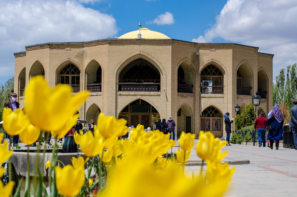 a large building with yellow flowers in front of it
