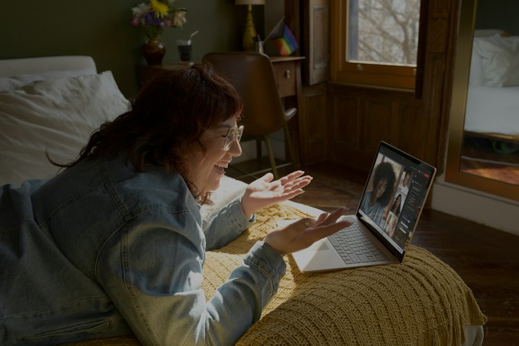 Person smiling while on a video call with a friend on a laptop