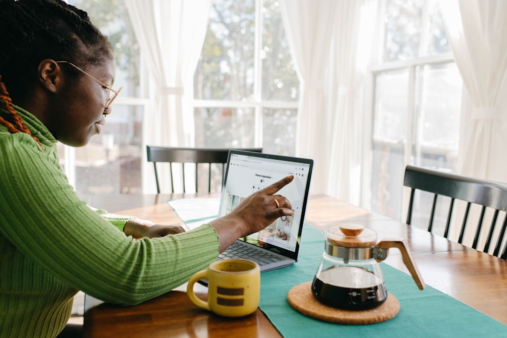 a woman sitting at a table using a laptop computer