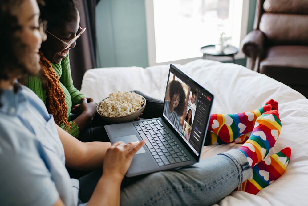 a couple of people sitting on a bed with a laptop