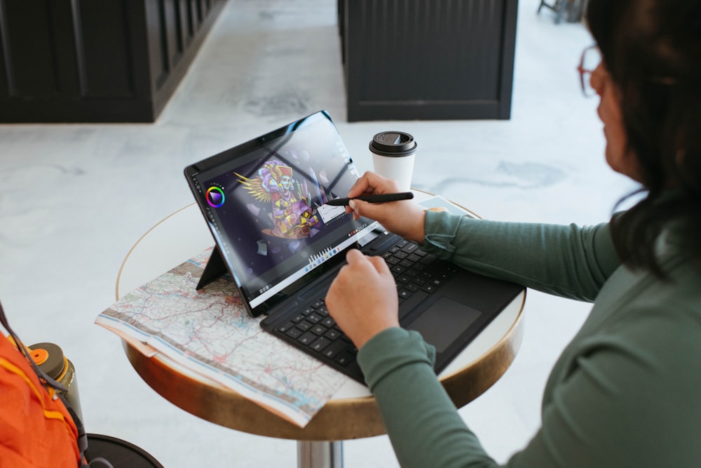 a woman sitting at a table using a laptop computer