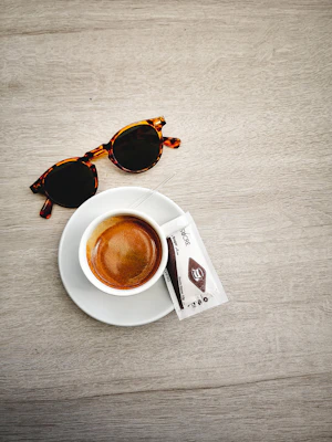 Classic eyeglasses with tortoiseshell frames sitting beside a coffee cup on a cozy café table.