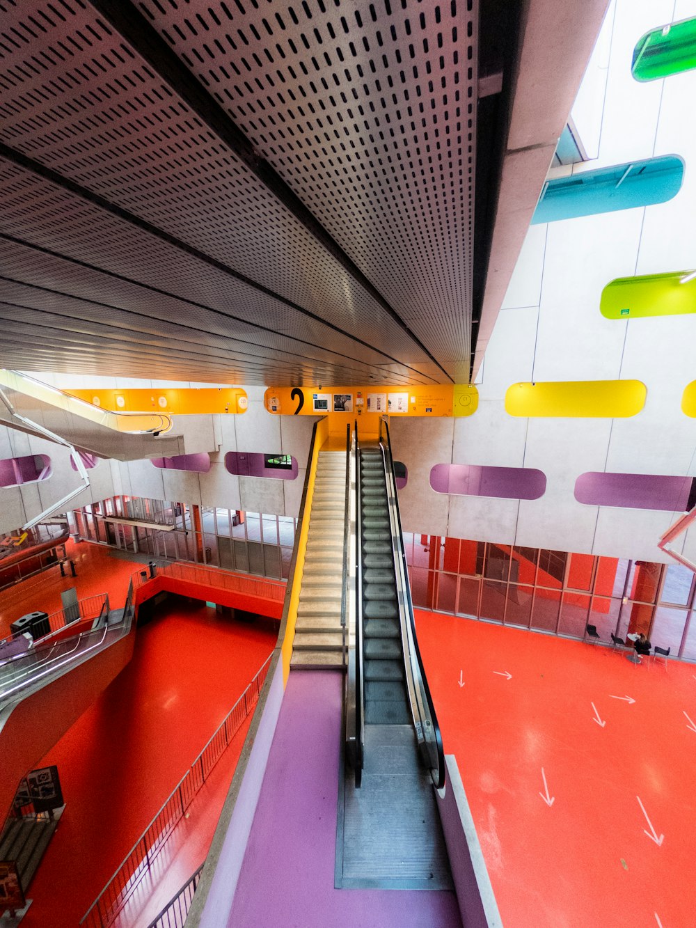 an escalator in a building with a colorful floor