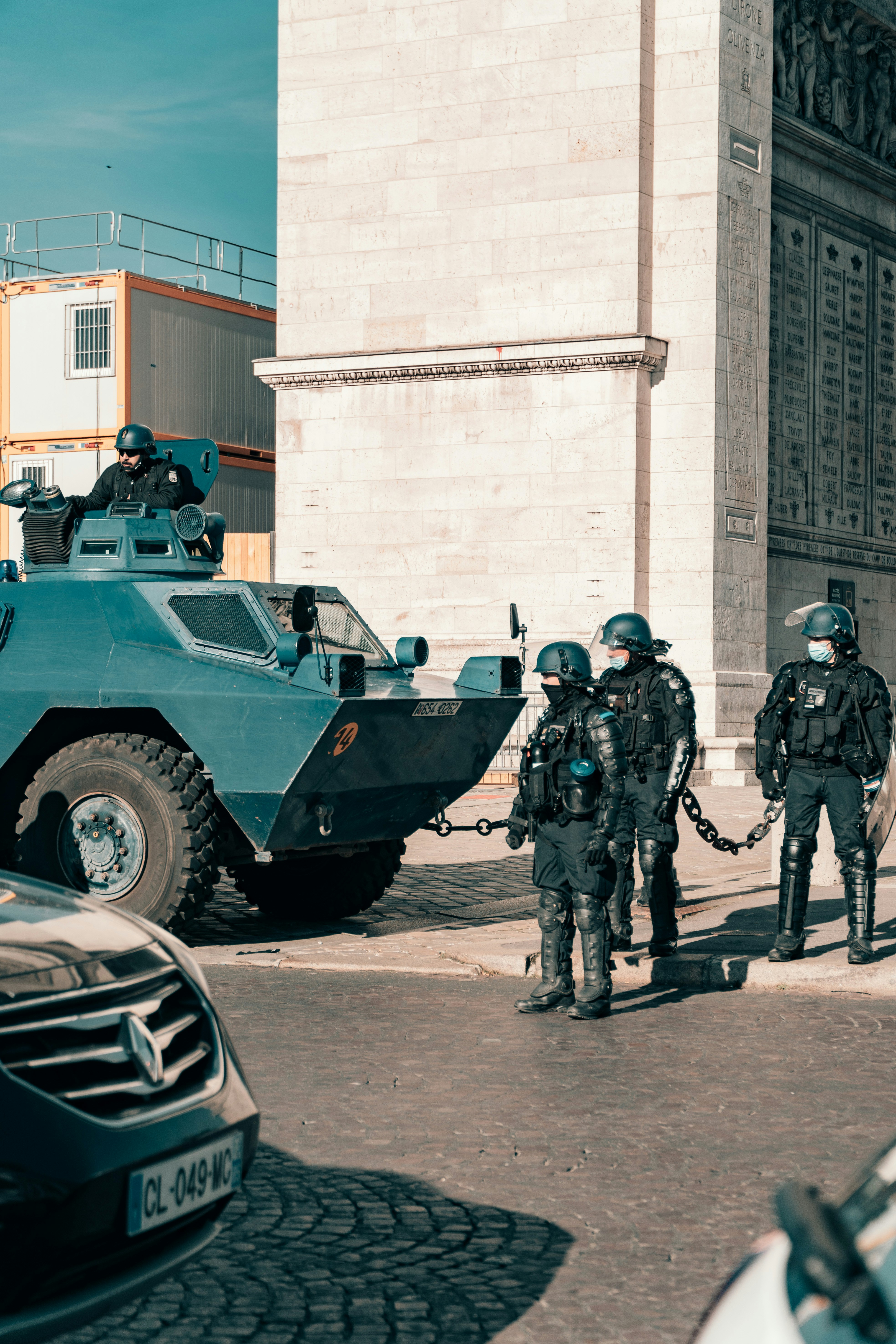 a group of men standing next to a blue armored vehicle
