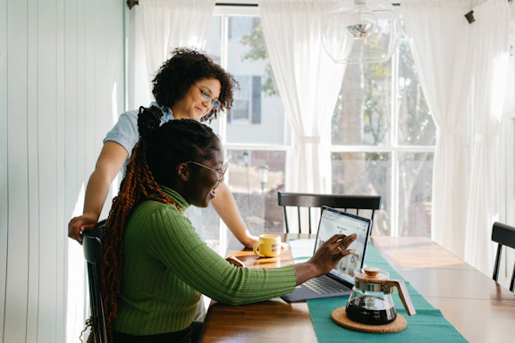 A warm, sunlit photo of a relaxed couple discussing crypto trades over coffee in a cozy, terracotta-toned room.