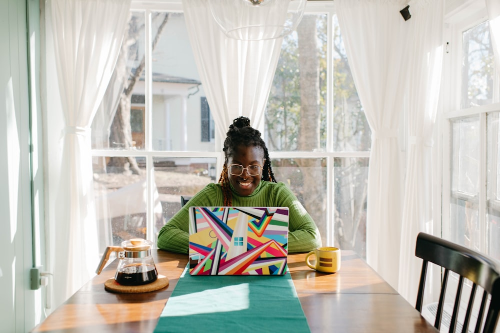 a woman sitting at a table using a laptop computer