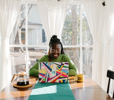 a woman sitting at a table using a laptop computer