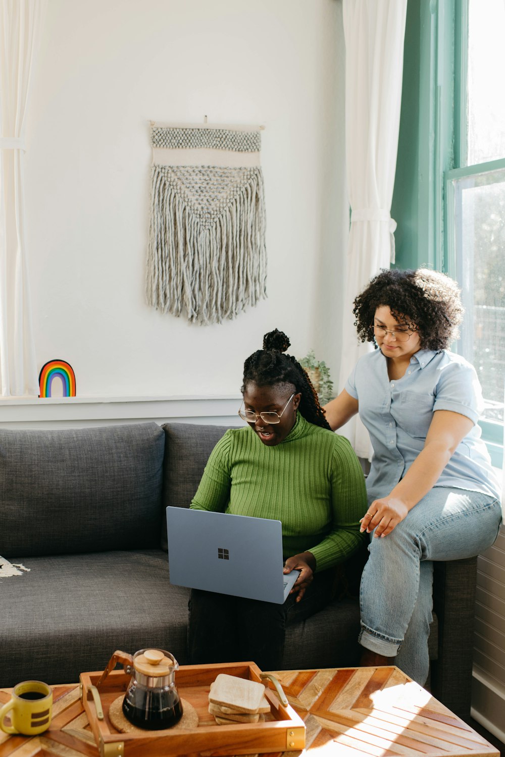 two women sitting on a couch looking at a laptop