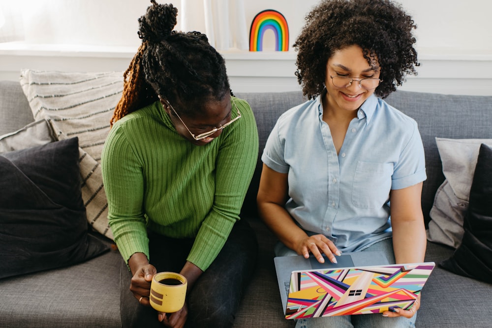 a couple of women sitting on top of a couch