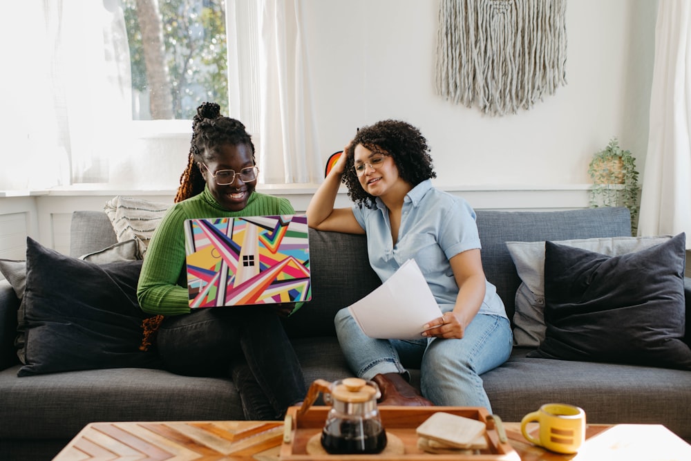 a couple of women sitting on top of a couch