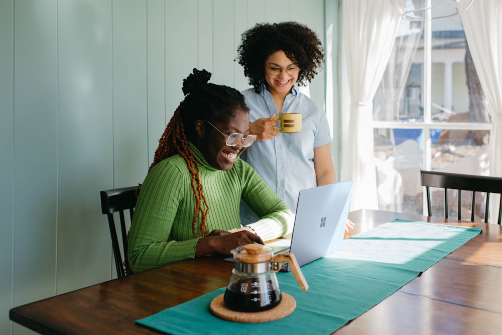 a couple of women sitting at a table with a laptop