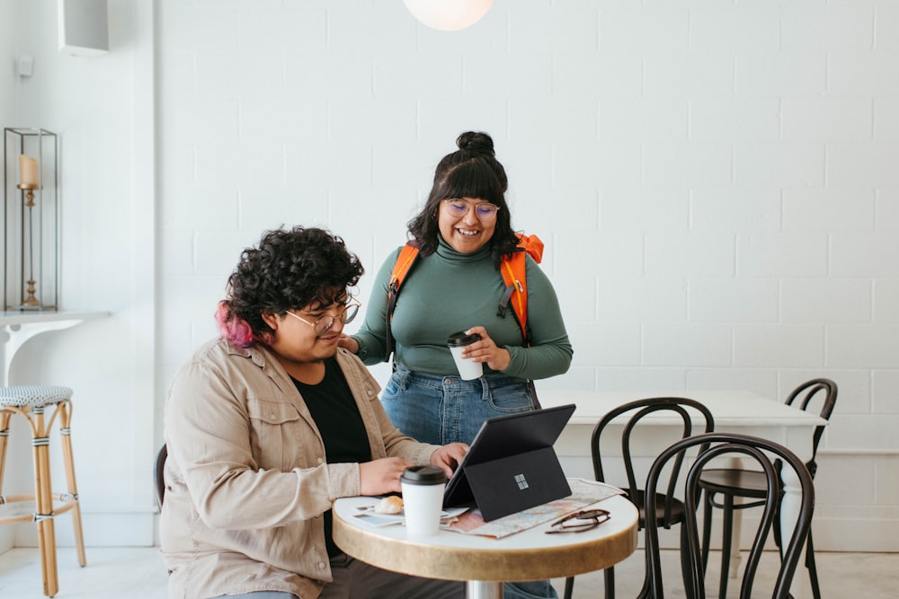 two people sitting at a table with a laptop