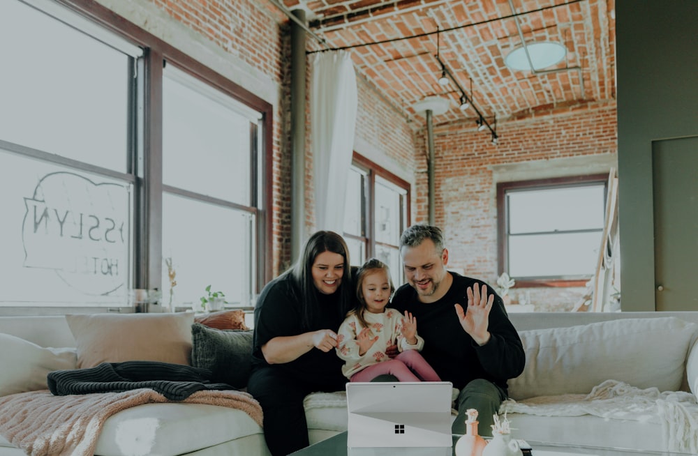 a man and woman sitting on a couch with a baby